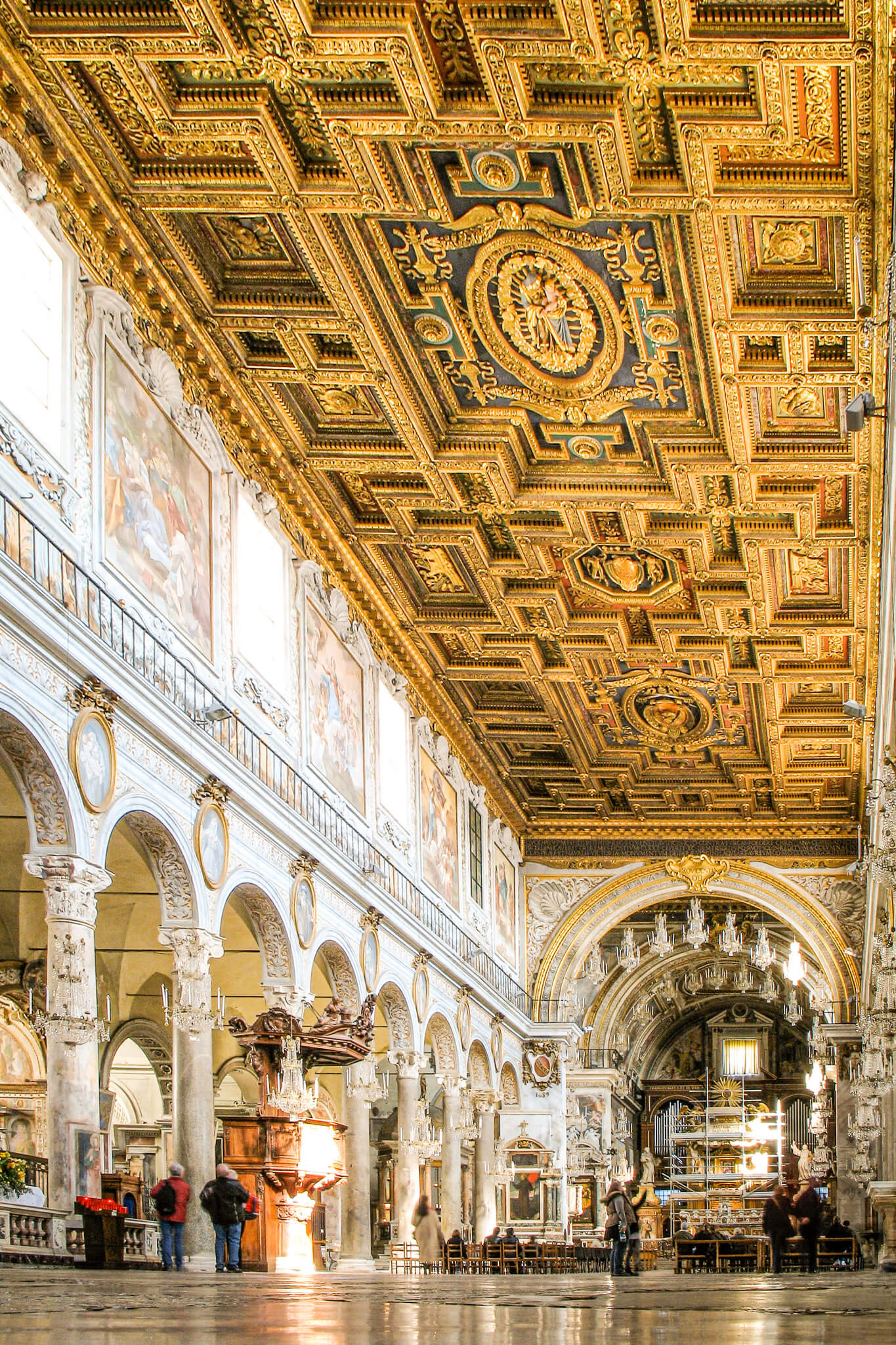 The ornate gilded ceiling and arches decorated with chandeliers inside the Santa Maria in Ara Cœli church