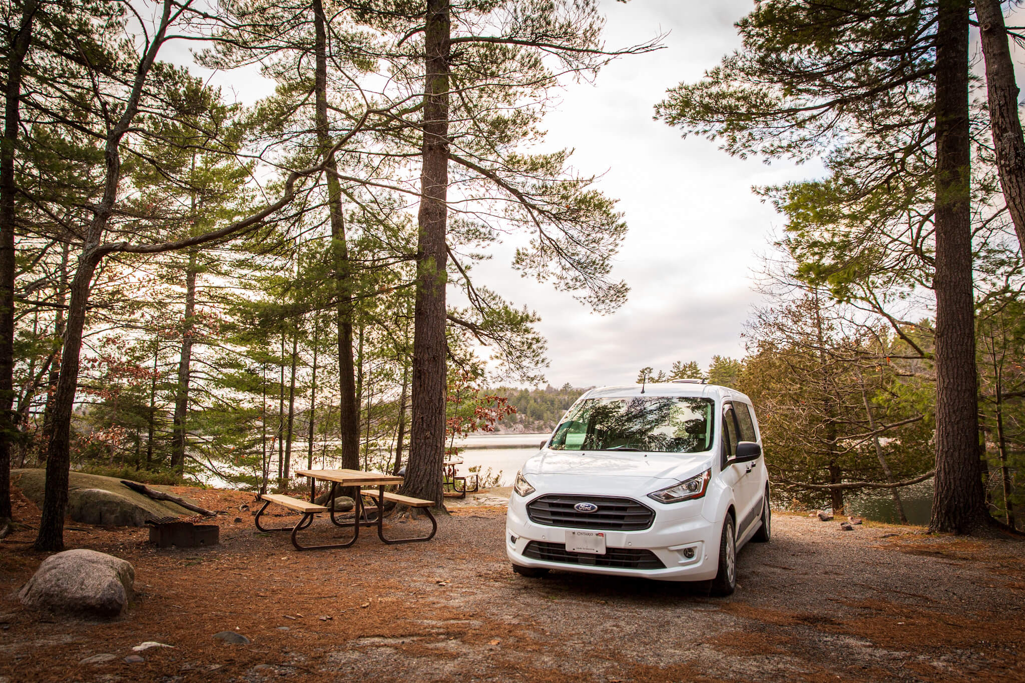 Transit Connect camper van on a lakefront camp site in Killarney Provincial Park