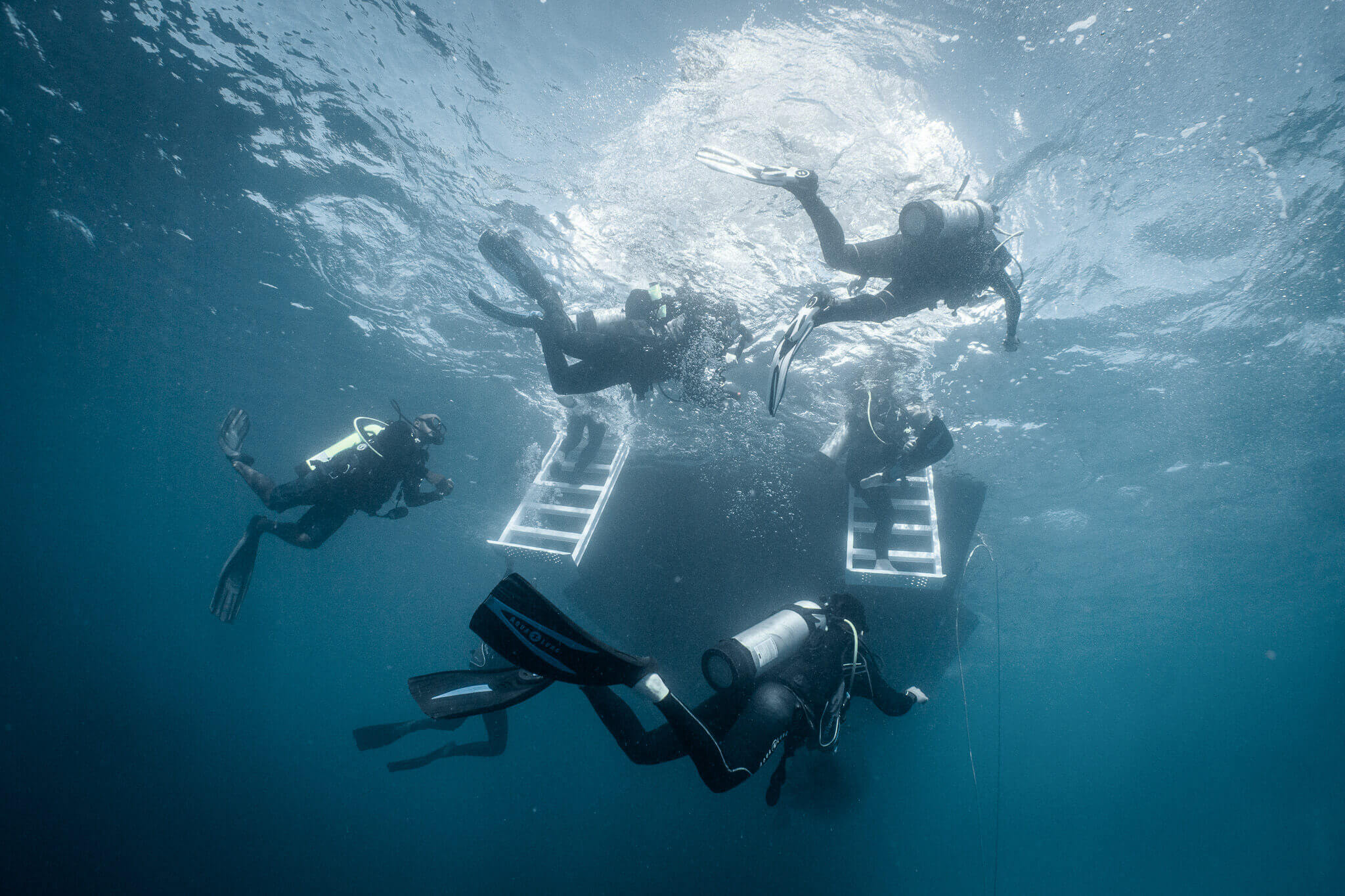 Divers underwater returning to the scuba liveaboard after a dive