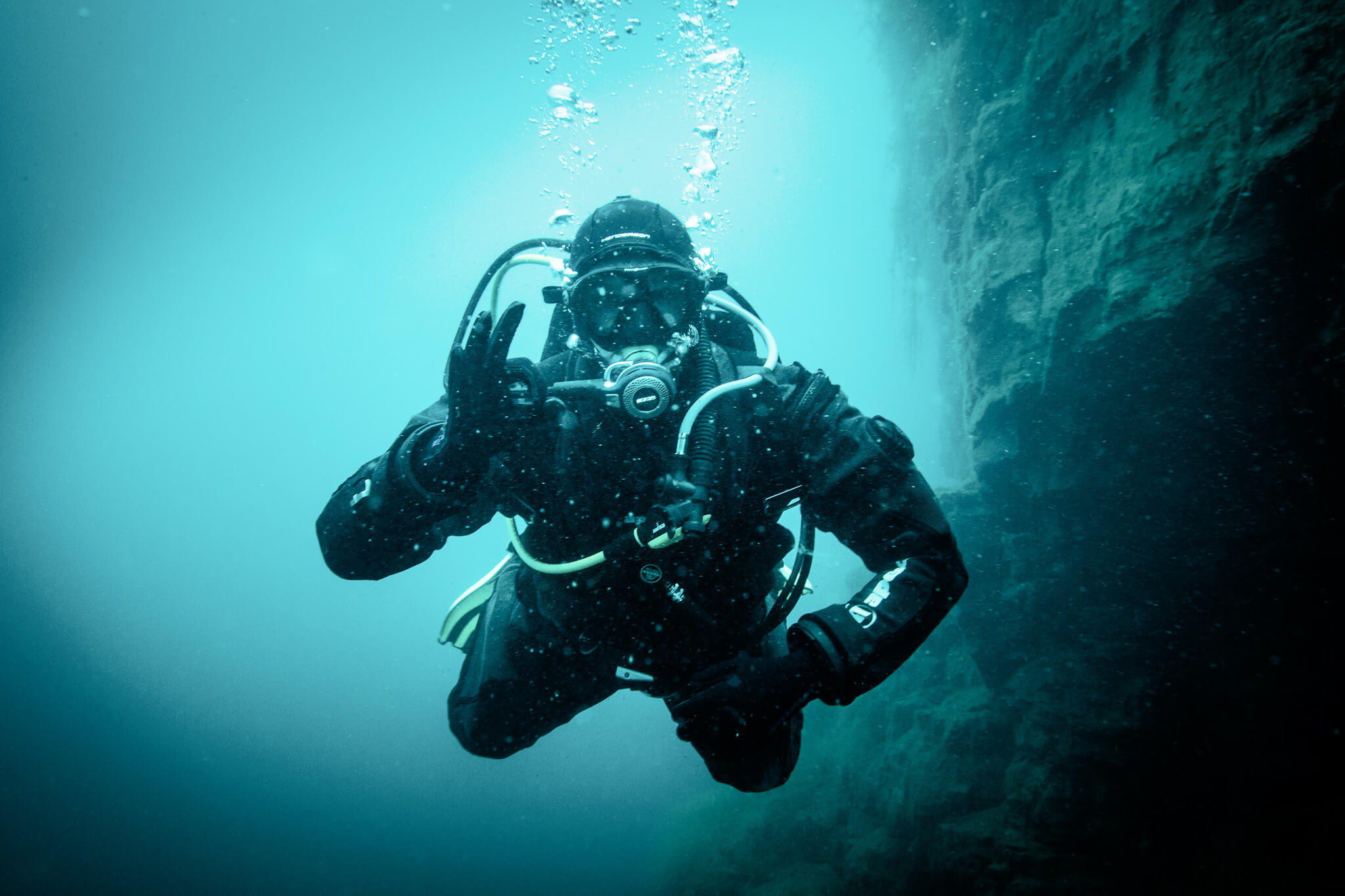 Scuba diver in a drysuit in a quarry giving the OK signal