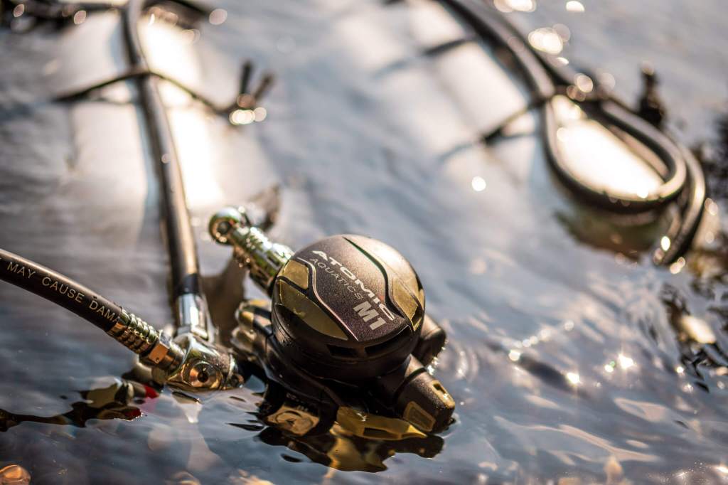Atomic Aquatics M1 regulator sets attached to sidemount scuba cylinders in shallow water
