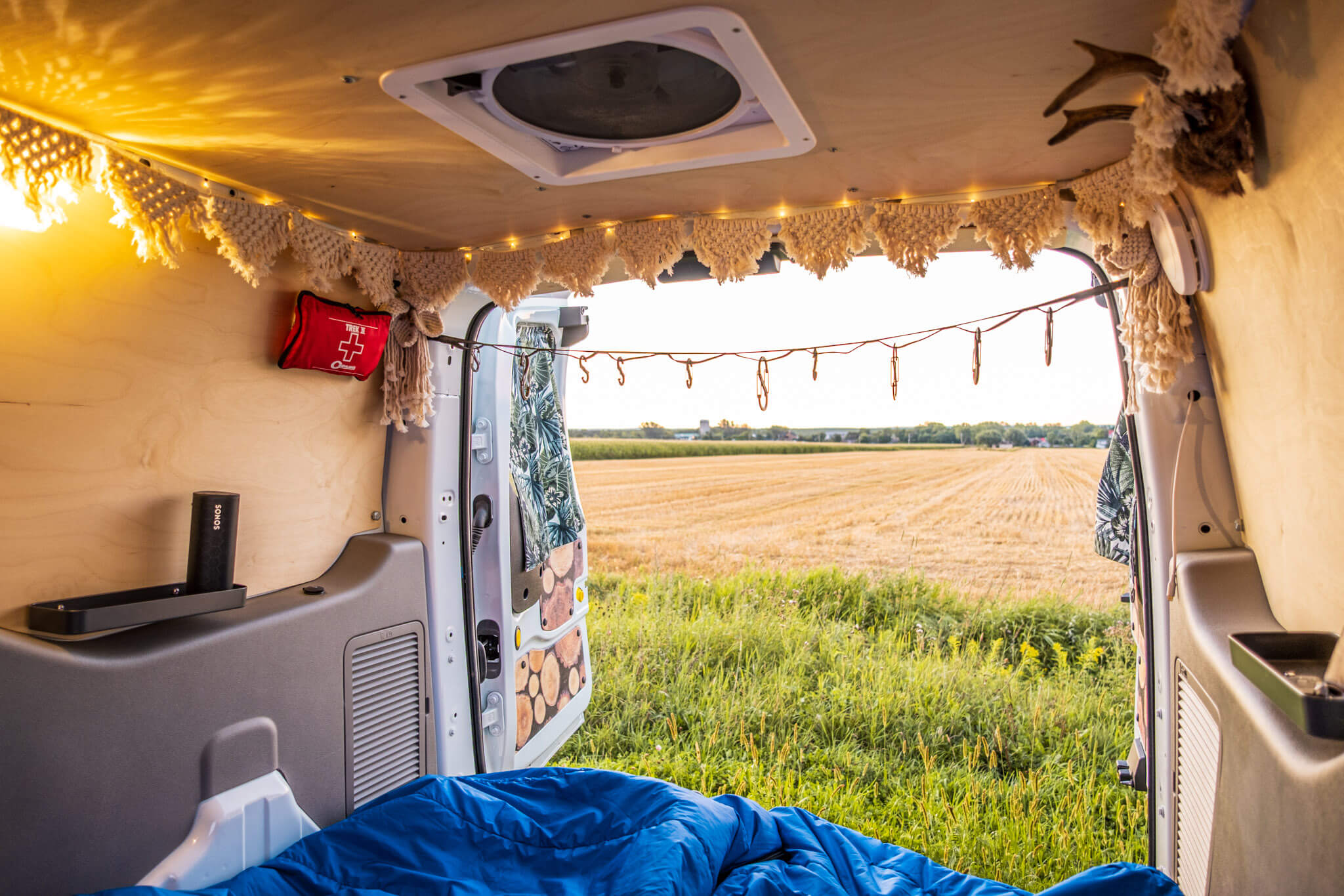 View of farm fields through the rear doors of a Ford Transit Connect camper van conversion