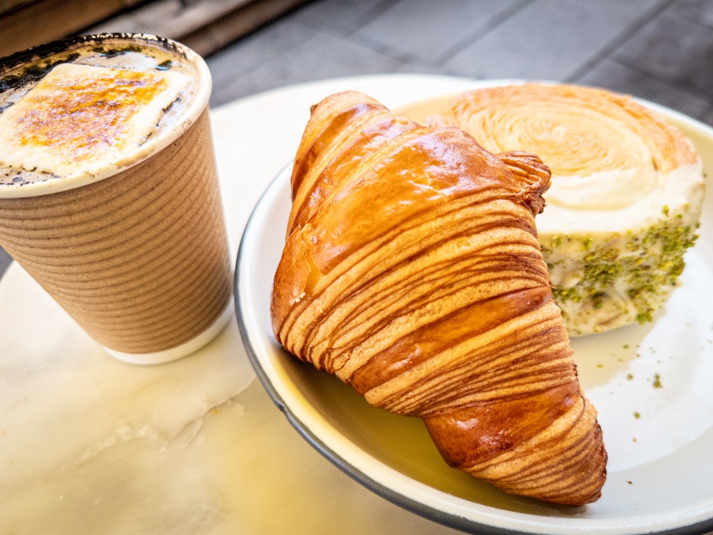 An artisanal croissant and pistachio pastry with a hot chocolate on a terrace in Old Montreal