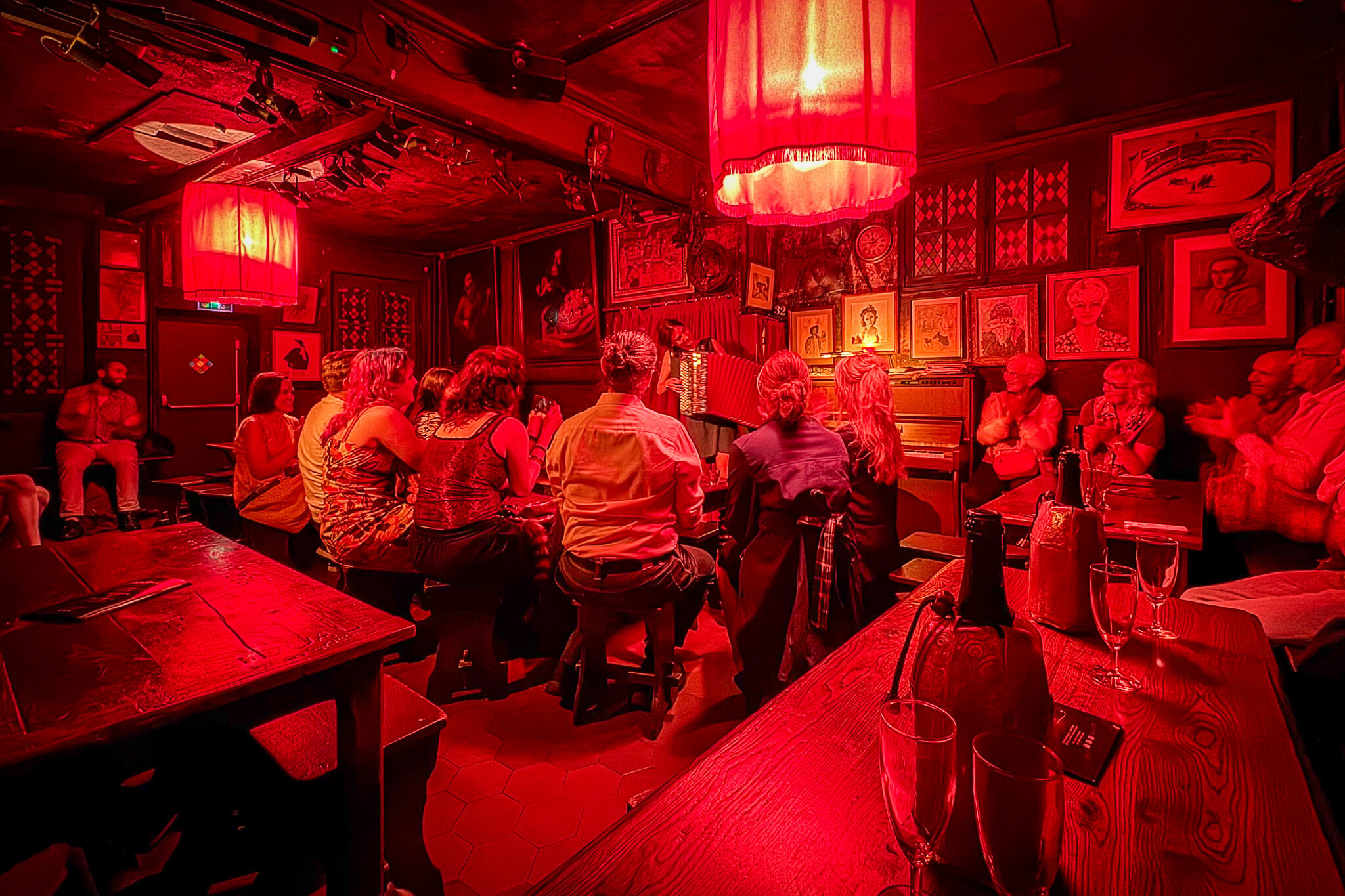 The interior of Au Lapin Agile in Montmartre during a cabaret performance featuring a singer with an accordion