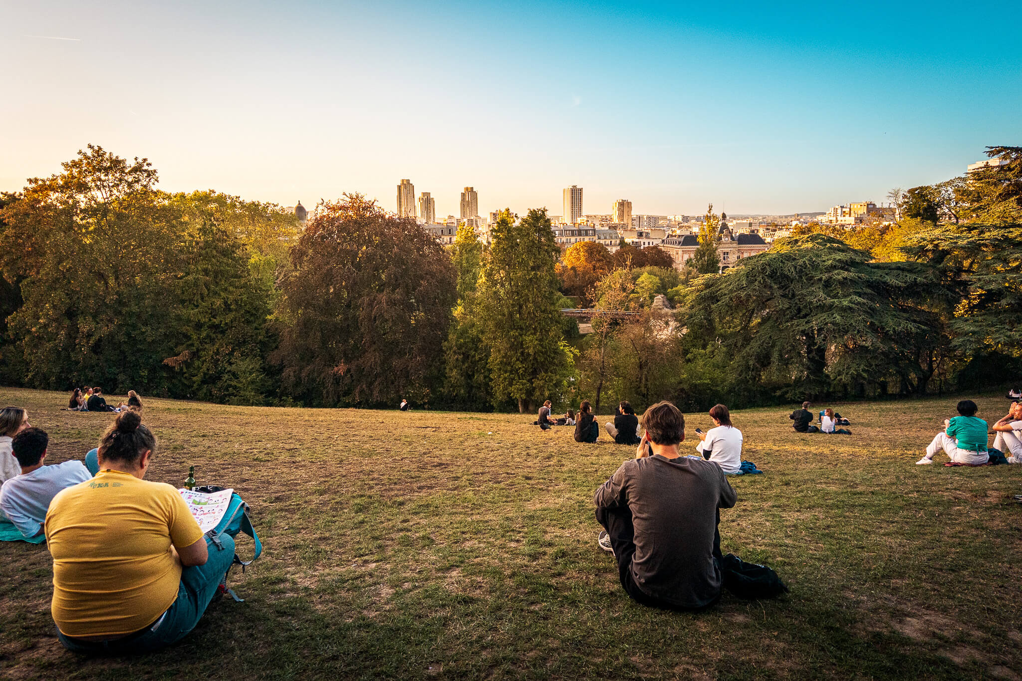 People gathering for sunset on a hillside in Parc des Buttes-Chaumont