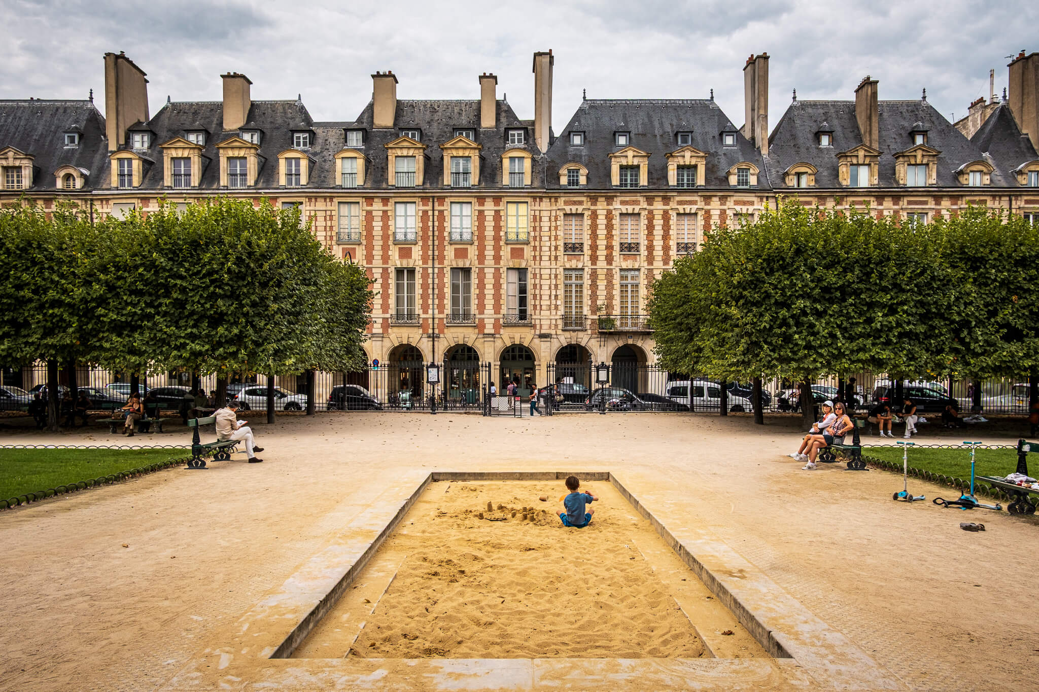 A sandpit in front of the brick townhouses of Place des Vosges in Paris