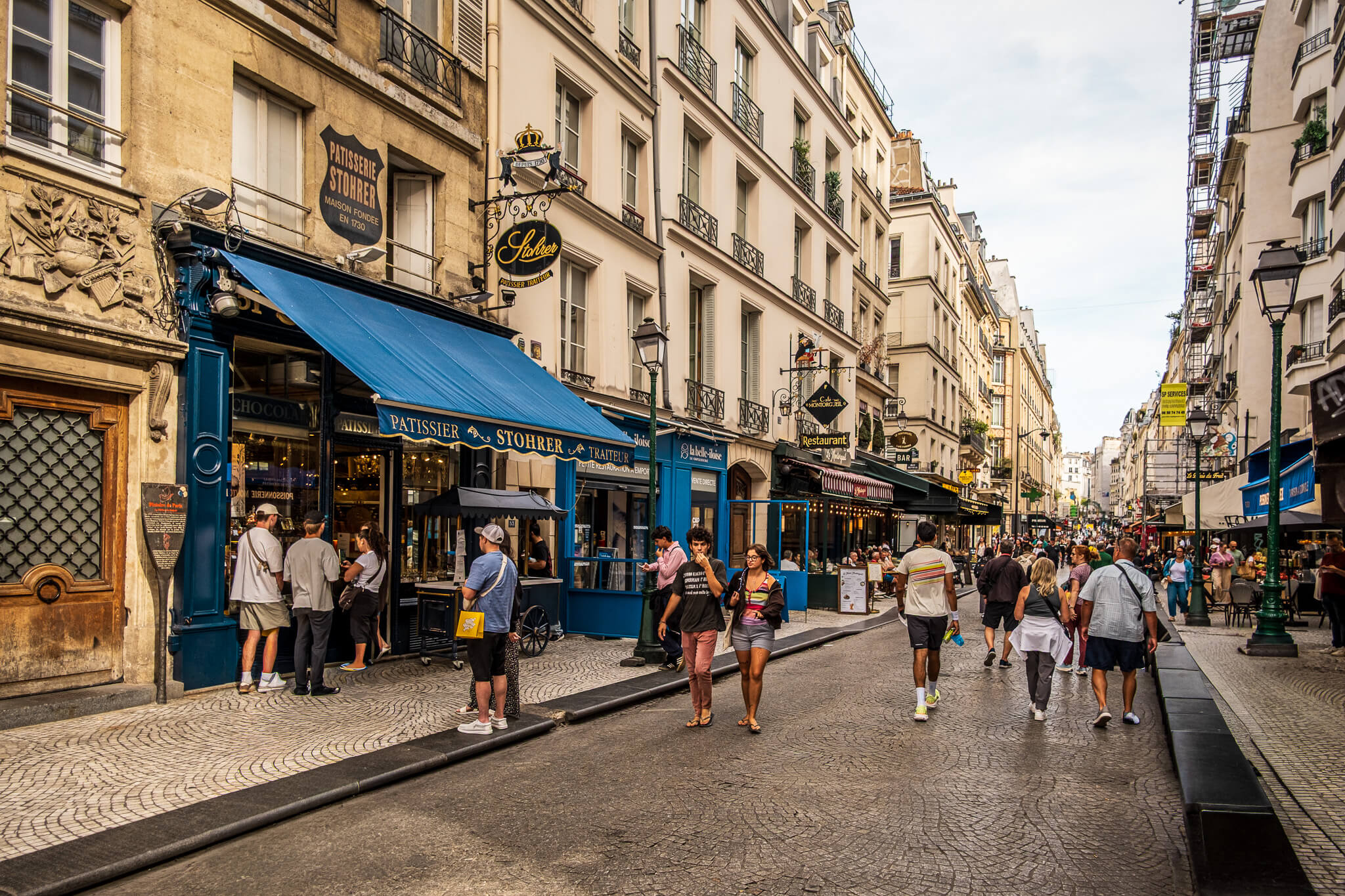 Foodie shops on Rue Montorgueil pedestrian street in Paris, with a focus on the Stohrer pastry shop